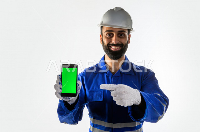 بورتريه لرجل اطفاء  سعودي خليجي ناجح ، معدات الازمة لاطفاء الحريق ، يستخدم هاتفه المحمول بخلفية خضراء كروما  ، يعمل في مجال الانقاذ ، يرتدي الزي الرسمي الخاص بمزاولة مهنة الدفاع المدني ، خلفية بيضاء