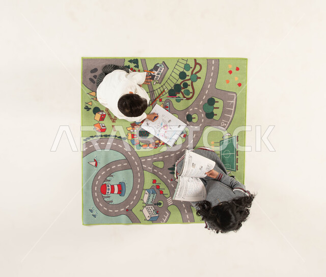 مشاركة النشاطات الترفيهية مع الأخوات, قضاء أوقات الفراغ بالاستمتاع بالرسم والتلوين, ممارسة هواية القراءة, تنمية المهارات الحركية والفنية ودعم المواهب, بورتريه علوي عامودي لأخوين عربيين خليجيين سعوديين يجلسان على سجادة بتصميم عصري, خلفية بيضاء