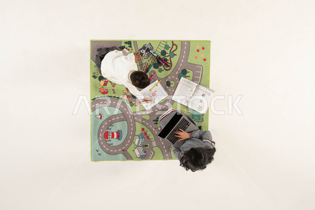 الاستمتاع بقضاء وقت ممتع ومفيد مع الأخوة, بورتريه علوي عامودي لولد وبنت عربين خليجين سعوديين إحداهما يقوم بالرسم والتلوين والأخرى تستخدم الحاسب المحمول, البحث عن معلومة ما عبر الانترنت, تنمية المهارات الفنية لدى الأطفال, خلفية بيضاء