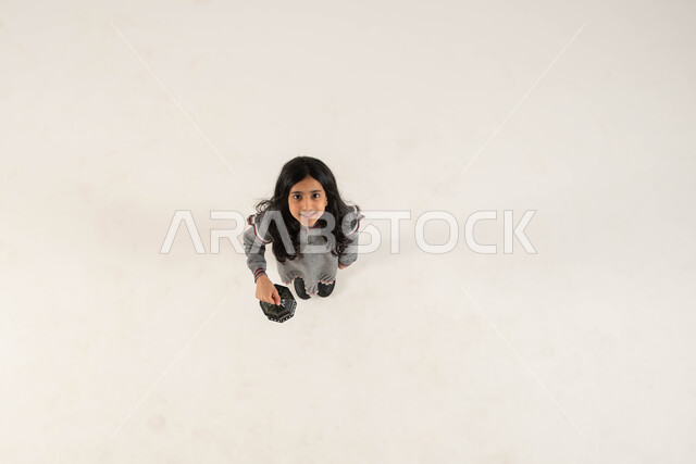 التزيين والتحضير للأجواء الروحانيه الرمضانيه، التجهيزات لاستقبال شهر رمضان المبارك، بورتريه علوي عامودي لفتاة عربيه خليجيه سعوديه مبتسمة تحمل بيدها الفانوس المعدني و تنظر الى الكاميرا، المناسبات الدينيه والأعياد الإسلامية، خلفيه بيضاء .