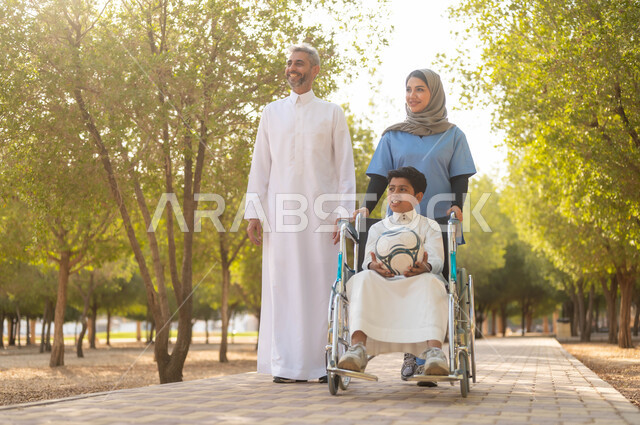 أب يتنزه في احدى الحدائق في الأجواء الصيفية مع ابنه، الاستعداد للعب بكرة القدم، الاهتمام بذوي الاحتياجات الخاصة، ممرضة عربية خليجية سعودية محجبة تقوم بمساعدة ولد يجلس على الكرسي المتحرك، تأمين ادوات تساعد أصحاب الهمم على التنقل، نمط الحياة في السعودية