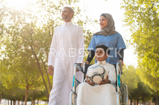 أب يتنزه في احدى الحدائق في الأجواء الصيفية مع ابنه، الاستعداد للعب بكرة القدم، الاهتمام بذوي الاحتياجات الخاصة، ممرضة عربية خليجية سعودية محجبة تقوم بمساعدة ولد يجلس على الكرسي المتحرك، تأمين ادوات تساعد أصحاب الهمم على التنقل، نمط الحياة في السعودية