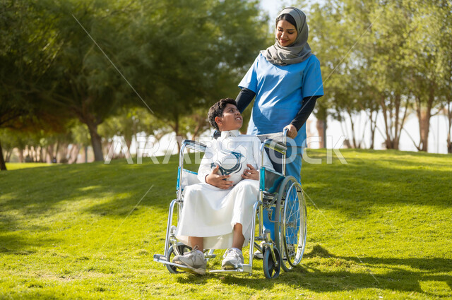 الاستعداد للعب بالكرة، الاهتمام بذوي الاحتياجات الخاصة، الاستمتاع  بالأجواء الصيفيه المشمسة، التنزه في احدى الحدائق، ممرضة عربية خليجية سعودية محجبة تقوم بمساعدة ولد يجلس على الكرسي المتحرك، تأمين ادوات تساعد أصحاب الهمم على التنقل، نمط الحياة في السعودية