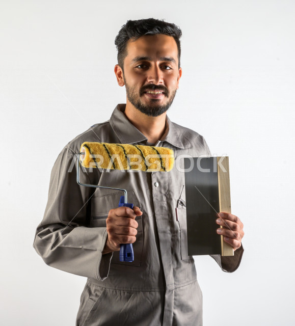 Portrait of a young Saudi Gulf man who works as a technical engineer, practicing his profession professionally, with skill and mastery of work, professional paint worker, paint craftsman, finishing tools, white background