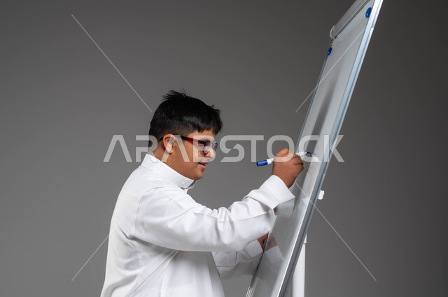 Saudi society’s support for people of determination and their education, a close-up portrait of a Saudi Gulf Arab young man with Down Syndrome, wearing a traditional dress and medical glasses, writing on a white board with expressions of integration, carrying out recreational and cultural activities, developing the artistic and intellectual capabilities of people with disabilities, gray background.