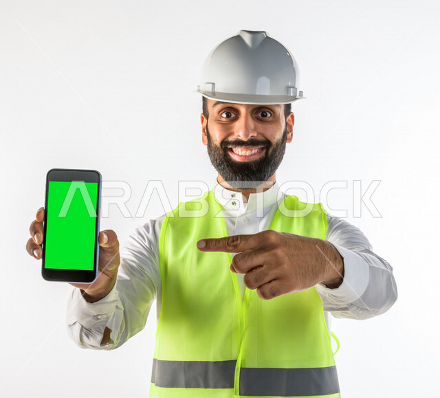 Portrait of a skilled Saudi engineer, professional in planning, using his mobile phone on a chroma green background, Gulf engineer man, white background