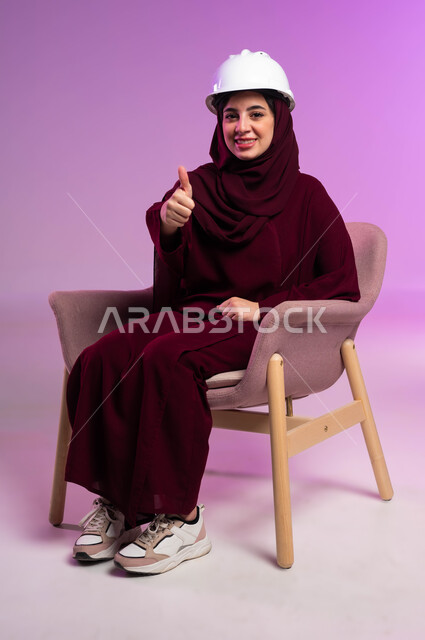 مفهوم الهندسة والانشاءات المعمارية، الجودة الفنية في تقنية التصميم والبناء، العمل في القطاع الهندسي, مهن ووظائف نسائية, بورتريه لمهندسة عربية خليجية سعودية ترتدي العباءة والخوذة البيضاء ترفع يدها بإيماءات الاعجاب والقبول, خلفية وردية