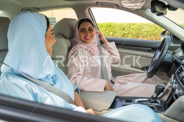 اتباع قواعد السلامة، تجهيز وتحضير السيارة قبل القيادة في الطرق والشوارع العامة، امرأتان عربيتان خليجيتان سعوديتان محجبتان تقومان بوضع حزام الأمان بايماءات السرور، قضاء وقت ممتع في الخارج مع الاصدقاء، مفهوم حرية القيادة للنساء السعوديات