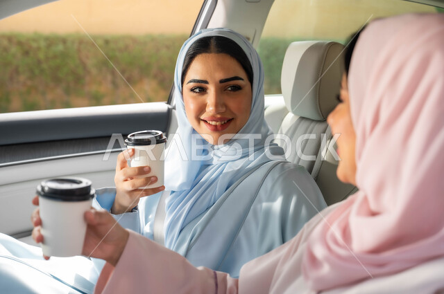تناول المشروبات الساخنه، التجول في شوارع المملكة ،قضاء أوقات ممتعه مع الأصدقاء، حرية القيادة للنساء السعوديات، صورة مقربة لامرأة عربيه خليجية سعودية محجبه تجلس في مقعد السيارة برفقة صديقتها بإيماءات السرور، مفهوم الاستقلال و الاعتماد على النفس في وسائل النقل