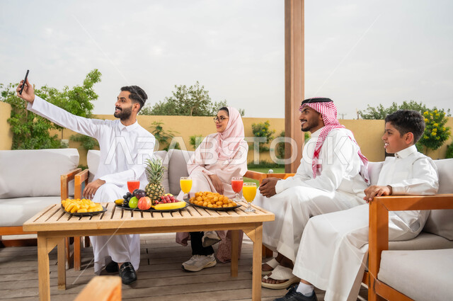 الاستمتاع في العطلة الصيفيه مع الاسرة، ايماءات السرور أثناء توثيق اللحظات السعيدة بالتقاط الصور التذكارية عبر الجوال، عائلة عربيه خليجيه سعودية تقضي أوقات الفراغ في إحدى الشاليهات، التنزه في الهواء الطلق