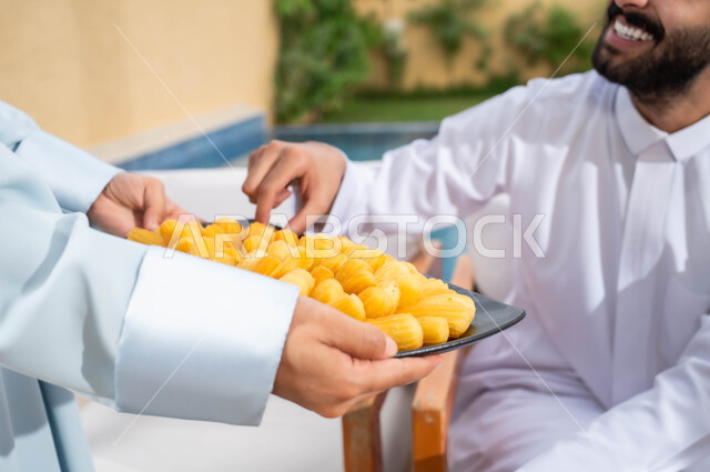 حسن الضيافه والاستقبال و إكرام الضيف, لمة الأسرة  السعيدة في إحدى الشاليهات، صورة مقربة بامرأة عربيه خليجيه سعودية تقوم بتقديم الحلويات العربية الشرقيه في التجمعات الأسرية، قضاء أوقات ممتعة مع الأهل والأصدقاء