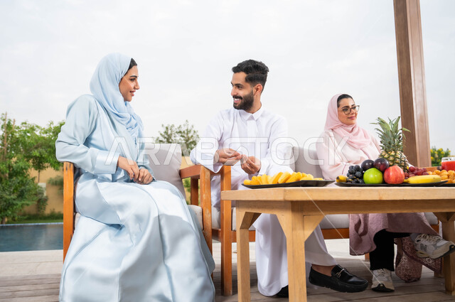 تناول الفواكة والمشروبات الصيفية المنعشة، الترفيه والتسليه في الهواء الطلق، قضاء أوقات ممتعة برفقه الأهل والأصدقاء في إحدى الشاليهات، أسرة عربيه خليجيه سعودية تقوم بتبادل الاحاديث والدردشات بإيماءات السرور والسعادة