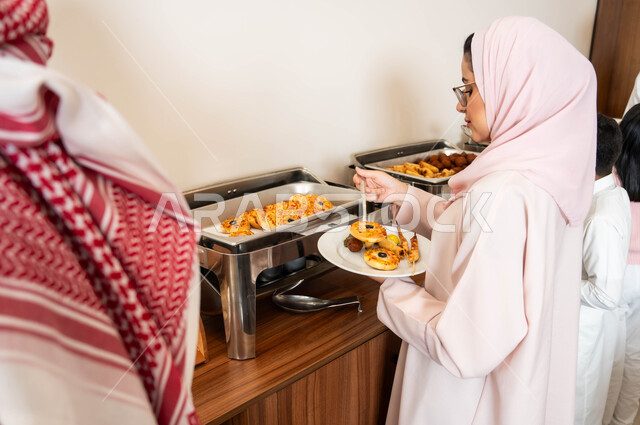 مفهوم الخدمة الذاتية في المطاعم السعودية، صورة مقربة من الخلف لزوجين عربيين خليجيين سعوديين يقومان بسكب الطعام من البوفيه في المطعم, قضاء اوقات عائلية ممتعه, اطباق متنوعه من المأكولات والمشروبات