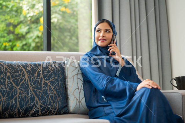 حوارات ودية مع الأهل والأصحاب، ايماءات وجه تدل على السعادة و السرور، امراة عربية سعودية خليجية ترتدي العباءة تجري اتصالات ومكالمات هاتفية، التواصل مع الأقارب والأصدقاء باستخدام الاجهزة التقنية الحديثة
