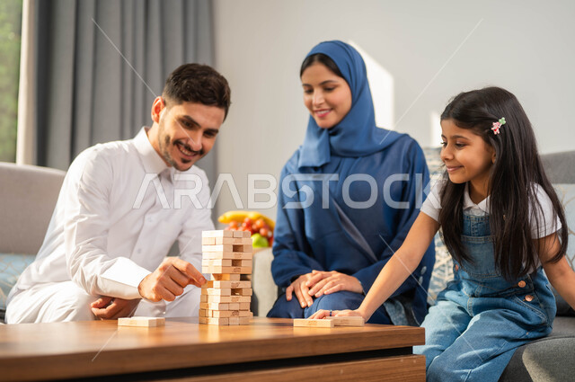 قضاء أوقات ممتعة مع الأبناء، جلسة عائلية في احدى الشاليهات الفاخرة، أب عربي يقوم بلعب لعبة الجينجا مع طفله، أجواء مليئة بالسعادة والسرور، أنشطة وفعاليات ترفيهية أسرية، مفهوم التحدي والمنافسة، صورة مقربة لعائلة عربية خليجية سعودية