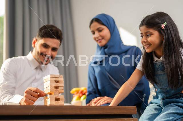 جلسة عائلية في احدى الشاليهات الفاخرة، أب عربي يقوم بلعب لعبة الجينجا مع طفله، أجواء مليئة بالسعادة والسرور، أنشطة وفعاليات ترفيهية أسرية، قضاء أوقات ممتعة مع الأبناء، مفهوم التحدي والمنافسة، صورة مقربة لعائلة عربية خليجية سعودية