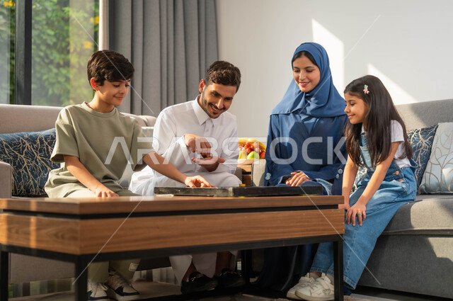 أنشطة وفعاليات ترفيهية أسرية، قضاء أوقات ممتعة مع الأبناء، مفهوم التحدي والمنافسة، جلسة عائلية في احدى الشاليهات الفاخرة، أب عربي يقوم بممارسة ألعاب الذكاء مع ابنه، عائلة عربية خليجية سعودية، أجواء مليئة بالسعادة والسرور