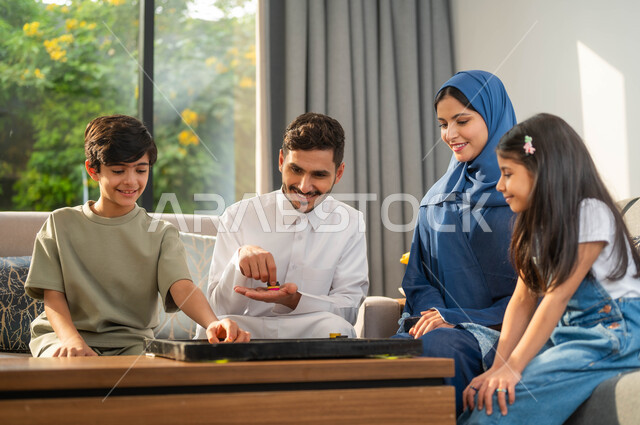 مفهوم التحدي والمنافسة، جلسة عائلية في احدى الشاليهات الفاخرة، أب عربي يقوم بممارسة ألعاب الذكاء مع ابنه، صورة مقربة لعائلة عربية خليجية سعودية، أجواء مليئة بالسعادة والسرور، أنشطة وفعاليات ترفيهية أسرية، قضاء أوقات ممتعة مع الأبناء