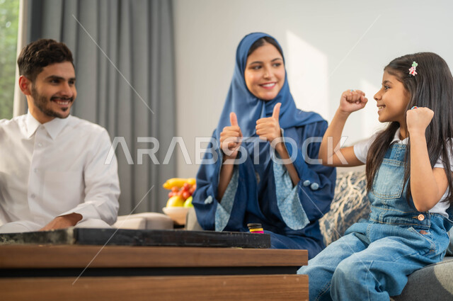 رفع اليدين بإيماءات مختلفة، جلسة عائلية في احدى الشاليهات الفاخرة، عائلة عربية خليجية سعودية تقضي وقت في اللعب، أجواء أسرية مليئة بالسعادة والسرور، مفهوم الترابط الاسري، قضاء أوقات ممتعة مع الأبناء، تبادل الاحاديث والدردشة بين أفراد الأسرة