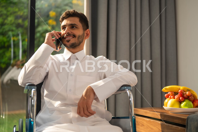 Hymrows of happiness and pleasure, conducting work communications, using modern technology and technologies, chatting and communicating with family and friends, a close image of an Arab Gulf Gulf, smiling seat wearing a traditional dress that uses a mobile phone, a lifestyle of people with determination