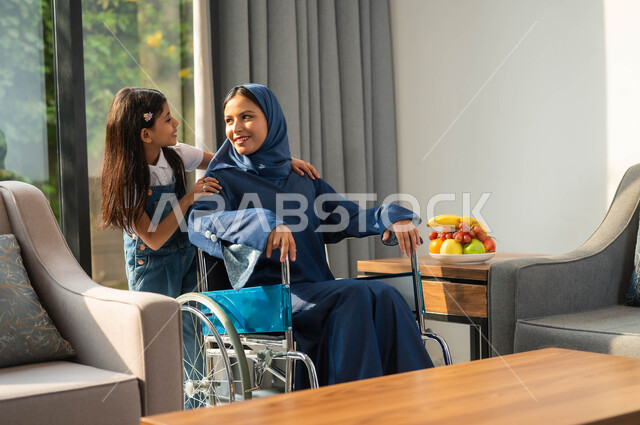 قضاء أوقات عائلية ممتعة، أسلوب حياة ذوي الهمم ، الاستمتاع بالجلسات الأسرية، دعم المجتمع السعودي لأصحاب الاحتياجات الخاصه، تأمين أدوات ومعدات تساعد على الحركة، صورة مقربة لامرأة عربية خليجية سعودية محجبة ترتدي عباءة تجلس مع طفلتها باحدى الشاليهات