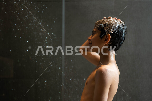 الشعور بالراحة الاسترخاء باستخدام الماء الساخن، مفهوم الاهتمام والعناية بالنظافة الشخصية، صورة مقربة لولد عربي خليجي سعودي يقوم بالاستحمام داخل إحدى الشاليهات الفاخرة في السعودية