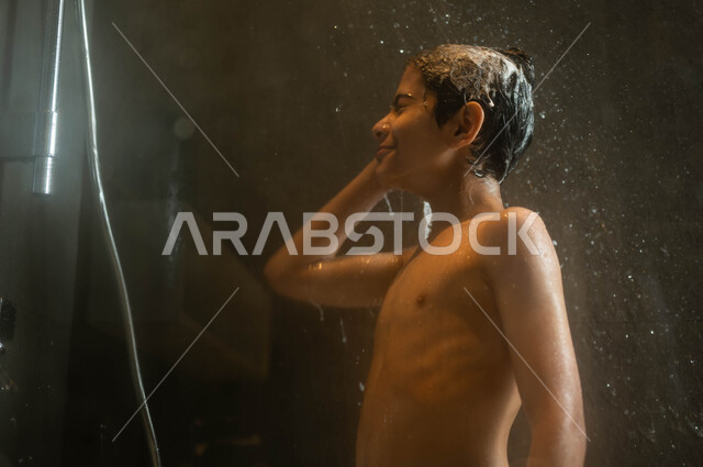 الاسترخاء والشعور بالراحة باستخدام الماء الساخن، مفهوم الاهتمام والعناية بالنظافة الشخصية، صورة مقربة لولد عربي خليجي سعودي يقوم بالاستحمام داخل إحدى الشاليهات الفاخرة في السعودية