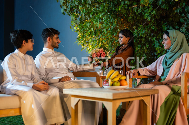 ابنه تقدم باقة من الزهور لوالدها، قضاء أوقات مسليه مع العائلة، مفهوم الترابط الأسري، جلسة عائلية في المساء داخل إحدى الشاليهات الفاخرة في المملكة العربية السعودية، فلل وشقق سياحية، إيماءات الفخر والأمتنان بالأب