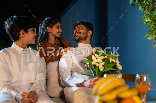 قضاء أوقات عائلية ممتعة، مفهوم الأبوة والاهتمام بالأولاد، ايماءات الفرح والسرور، عائلة عربية سعودية خليجية سعيدة في إحدى الشاليهات الفاخرة ، رعاية الأب لأبنائه والاستماع لهم، نظرة الأبنه لوالدها