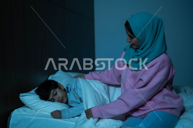 طفل ينام في سرير منعش ومريح على وسادة بيضاء ناعمة، أم عربية خليجية سعودية تطمئن على ولدها قبل النوم، مفهوم العناية والاهتمام بالأبناء، فوائد النوم المبكر، الاسترخاء والاستمتاع بالأجواء الهادئة، اتباع أسلوب حياة صحي