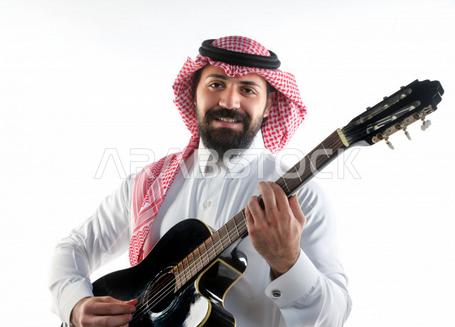 بورتريه شاب سعودي عربي خليجي يعزف على  الجيتار( آلة وترية) ، شاب باللباس السعودية التقليديه بخلفية بيضاء ، آلة موسيقية ، مجال صوتي و فني
