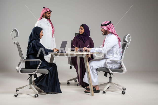 النجاح في تحقيق اهداف الشركة, توفير بيئة عمل مريحة، مفهوم روح الفريق والإنجاز الجماعي, تطوير الاستراتيجيات و الأعمال,  استخدام الاجهزة والتقنيات الحديثة في انجاز المهام المكتبية, بورتريه مقرب لموظفين عرب سعوديين خليجيين في اجتماع, خلفية رمادية