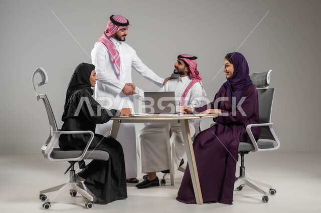 النجاح وتحقيق الاهداف, استخدام الاجهزة والتقنيات الحديثة في انجاز الاعمال المكتبية, المصافحة بإيماءات السرور والترحيب بالزميل الجديد، الحوارات والنقاشات ضمن الفريق, توفير بيئة عمل مناسبة, بورتريه مقرب لموظفين عرب سعوديين خليجيين في اجتماع, خلفية رمادية