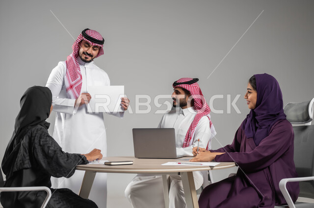 تطوير الخطط والاستراتيجيات، إيماءات الشرح والتوضيح، الحوارات والنقاشات بين الزملاء، بورتريه لموظف عربي خليجي سعودي يرتدي الشماغ والثوب التقليدي يحمل بيده أوراق, استخدام التقنيات الالكترونية الحديثة،  خلفية رمادية