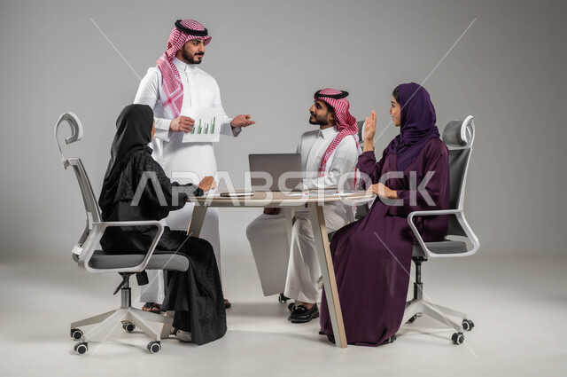 Study and analysis of new projects and plans, dialogues and discussions among colleagues, requesting a letter to discuss opinions, a portrait of Saudi Gulf Arab employees exchanging opinions, the concept of focus, hard work and professionalism in achievement, the use of modern electronic technologies, a gray background