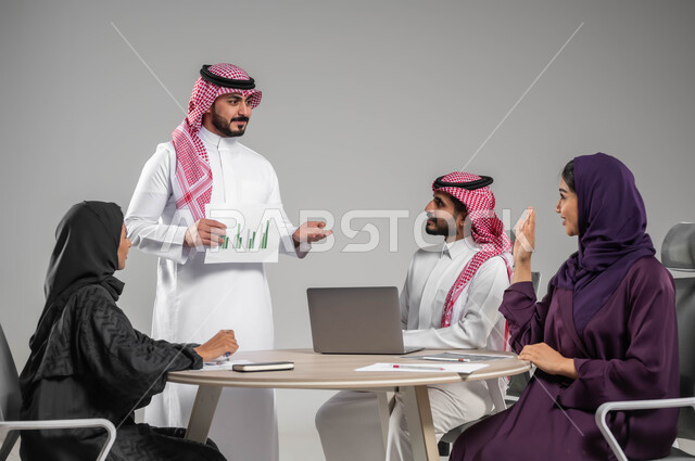طلب الإذن لمشاركة الأفكار، الحوارات والنقاشات بين الزملاء، شرح المخططات والرسوم البيانية، بورتريه لموظفين عربيين خليجيين سعوديين يتبادلون الآراء, مفهوم التركيز والعمل الجاد والاحترافية في الإنجاز، استخدام التقنيات الالكترونية الحديثة،  خلفية رمادية
