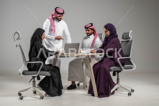 تدوين الملاحظات الهامة، مفهوم التركيز والدقة في الإنجاز، الإشارة إلى اللابتوب بإيماءات الشرح وتوضيح المهام المطلوبة، الحوارات والنقاشات بين الزملاء، بورتريه لفريق عربي خليجي سعودي في اجتماع, ورشات عمل وتدريب، خلفية رمادية