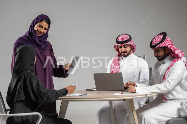 شرح المهام المطلوبة بسعادة وحب, التعاون والتفاهم بين الفريق, تبادل الخبرات والاتفاقيات الناجحة, بورتريه لزملاء عمل عرب سعوديين خليجيين في اجتماع, ارتداء اللباس السعودي التقليدي, بيئة العمل المريحة في الشركة السعودية, خلفية رمادية