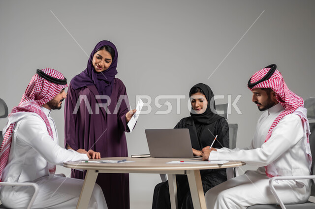 Business meeting and project completion, focus and careful work, dialogues and discussions within the team, business and company development, discussion of plans and explanation of business tasks, portrait of Saudi Gulf Arab co-workers in a meeting, wearing traditional Saudi dress, gray background