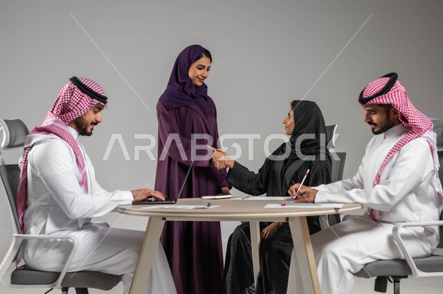 الاحترافية والتفاني في الانجاز, المصافحة والاتفاق في تطوير الاعمال, تبادل الخبرات والمعلومات الناجحة, التعاون والتفاهم بين الفريق, تعابير الصداقة العميقة, بورتريه لزملاء عرب سعوديين خليجيين في اجتماع, ارتداء اللباس السعودي التقليدي, خلفية رمادية