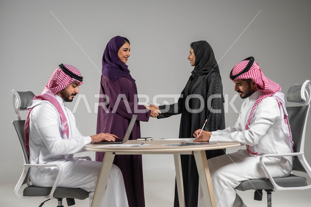 تبادل الخبرات والاتفاقيات الناجحة, التعاون والتفاهم بين الفريق, تعابير الصداقة العميقة, بورتريه لزملاء عرب سعوديين خليجيين في اجتماع, ارتداء اللباس السعودي التقليدي, بيئة العمل المريحة في الشركة السعودية, خلفية رمادية