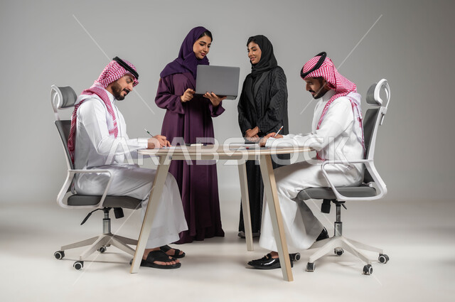 المساعدة والتعاون في تطوير الاعمال, مهن ووظائف سعودية, استخدام التقنيات الحديثة في تطوير العمل, بورتريه لموظفين عرب سعوديين خليجيين في اجتماع, ارتداء اللباس السعودي التقليدي, خلفية رمادية
