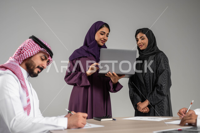 مفهوم الشراكة والعمل الجماعي, اكتساب الخبرة وتوسيع الخطط المهنية, بورتريه لزملاء عرب سعوديين خليجيين في اجتماع, ارتداء اللباس السعودي التقليدي, الاشارة الى الحاسوب بهدف توضيح المعلومات, استخدام الاجهزة والتقنيات الحديثة في تطوير الاعمال, خلفية رمادية