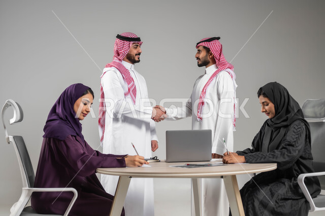 المصافحة والاتفاق في تطوير الاعمال, اكتساب الخبرة وتوسيع شبكة العلاقات المهنية, توفير بيئة عمل مناسبة, بورتريه لموظفين عرب سعوديين خليجيين في اجتماع, ارتداء اللباس السعودي التقليدي ضمان فهم واضح وشامل للعمل, خلفية رمادية