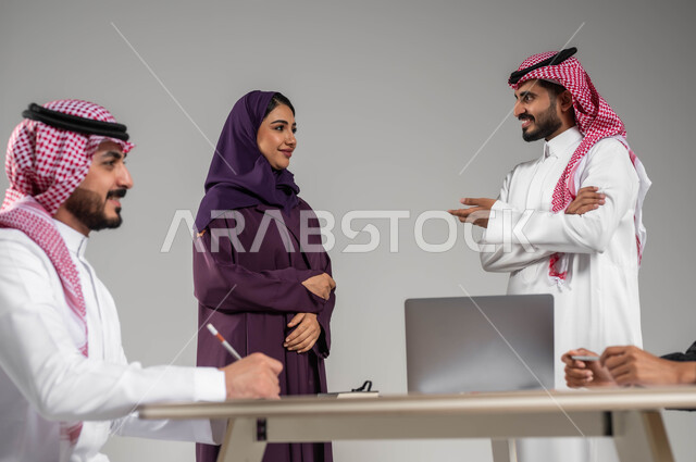 مهن ووظائف سعودية, التفاهم والتعاون في العمل, توفير بيئة عمل مناسبة, بورتريه مقرب لموظفين عرب سعوديين خليجيين في اجتماع, ارتداء اللباس السعودي التقليدي, استخدام الاجهزة في انجاز الاعمال المكتبية, خلفية رمادية