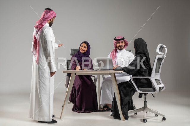 مفهوم الشراكة والتعاون, الحوارات والنقاشات ضمن الفريق, توفير بيئة عمل مناسبة, بورتريه لموظفين عرب سعوديين خليجيين في اجتماع, ارتداء اللباس السعودي التقليدي, النجاح وتحقيق الاهداف, استخدام الاجهزة والتقنيات الحديثة في انجاز الاعمال المكتبية, خلفية رمادية