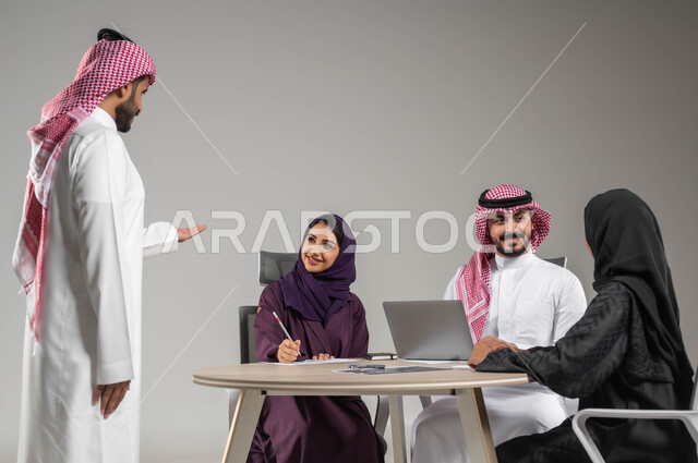 الحوارات والنقاشات ضمن الفريق, مفهوم الشراكة والتعاون, توفير بيئة عمل مناسبة, بورتريه مقرب لموظفين عرب سعوديين خليجيين في اجتماع, ارتداء اللباس السعودي التقليدي, النجاح وتحقيق الاهداف, استخدام الاجهزة والتقنيات الحديثة في انجاز الاعمال المكتبية, خلفية رمادية