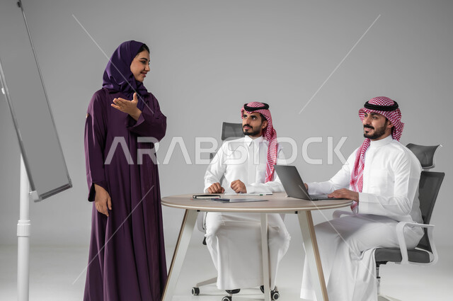 العمل الجماعي وروح الفريق، مناقشة خطط العمل، ضمان فهم واضح وشامل للاعمال، استعمال السبورة لتوضيح العمليات والاجراءات المتبعة في الشركة، استخدام اللابتوب في تدوين الملاحظات، الاحترافية والتفاني في الإنجاز، بورتريه لفريق عربي خليجي سعودي في اجتماع، خلفية رمادية