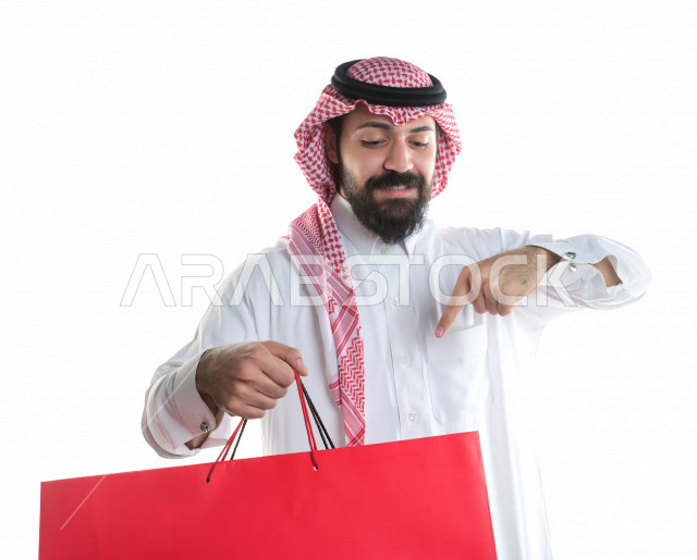 Portrait of a Saudi Gulf man carrying shopping bags, buying gifts, entertainment and shopping, on a white background