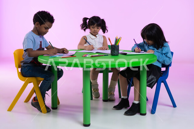 Skills development, education and creativity, drawing techniques for pre-school, recreational and artistic activities in kindergarten, portrait of Saudi Gulf Arab children wearing casual clothes practicing drawing coloring activity, pink background